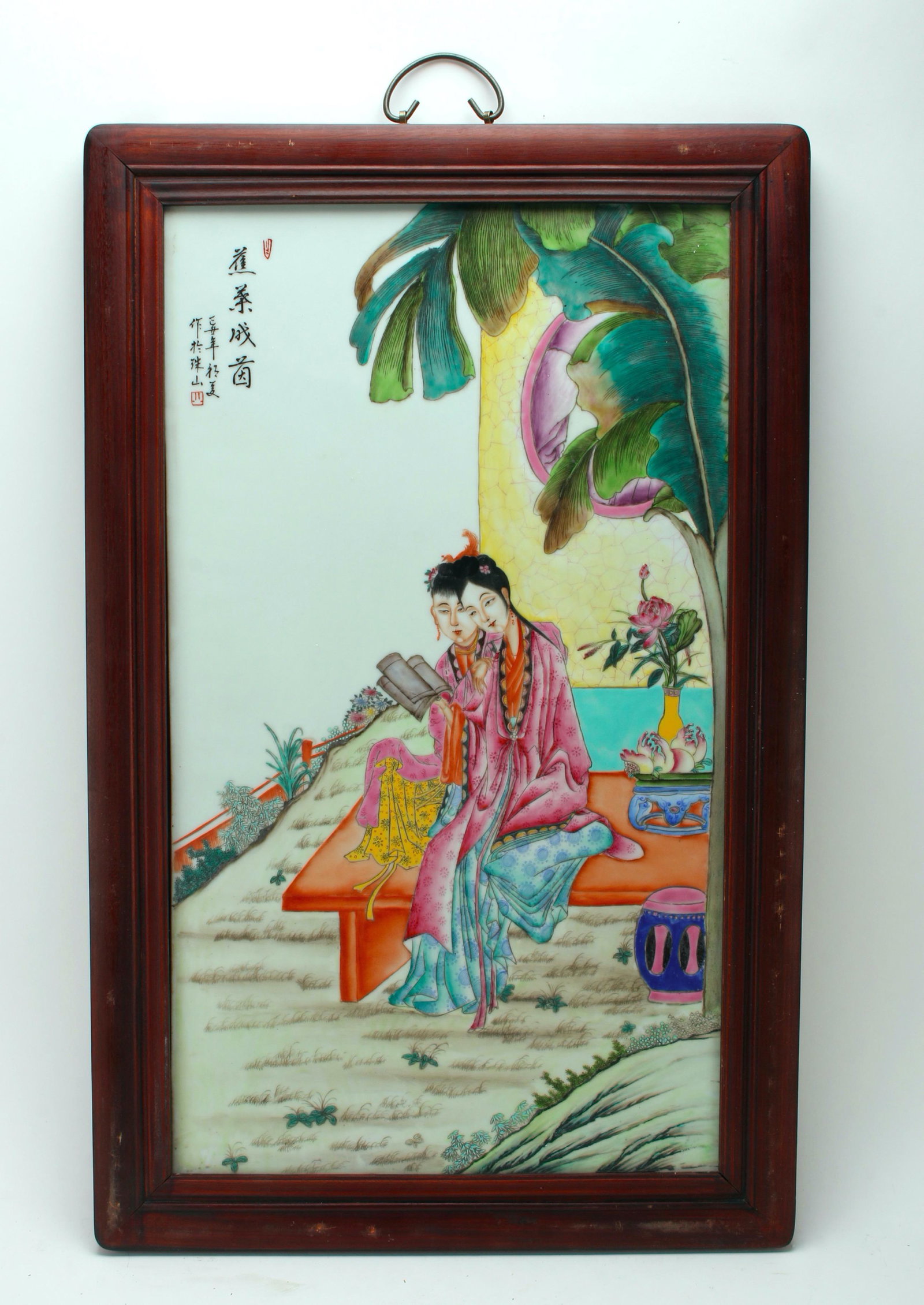 LARGE FRAMED PORCELAIN PLAQUE OF BEAUTIES: Beauties in a garden sitting on a bench outside of a house. A flower arraignment with peonies and Hands of Buddha. Calligraphy and artist marks on upper left. Bronze handle at top. 20" X 31 1/2&q