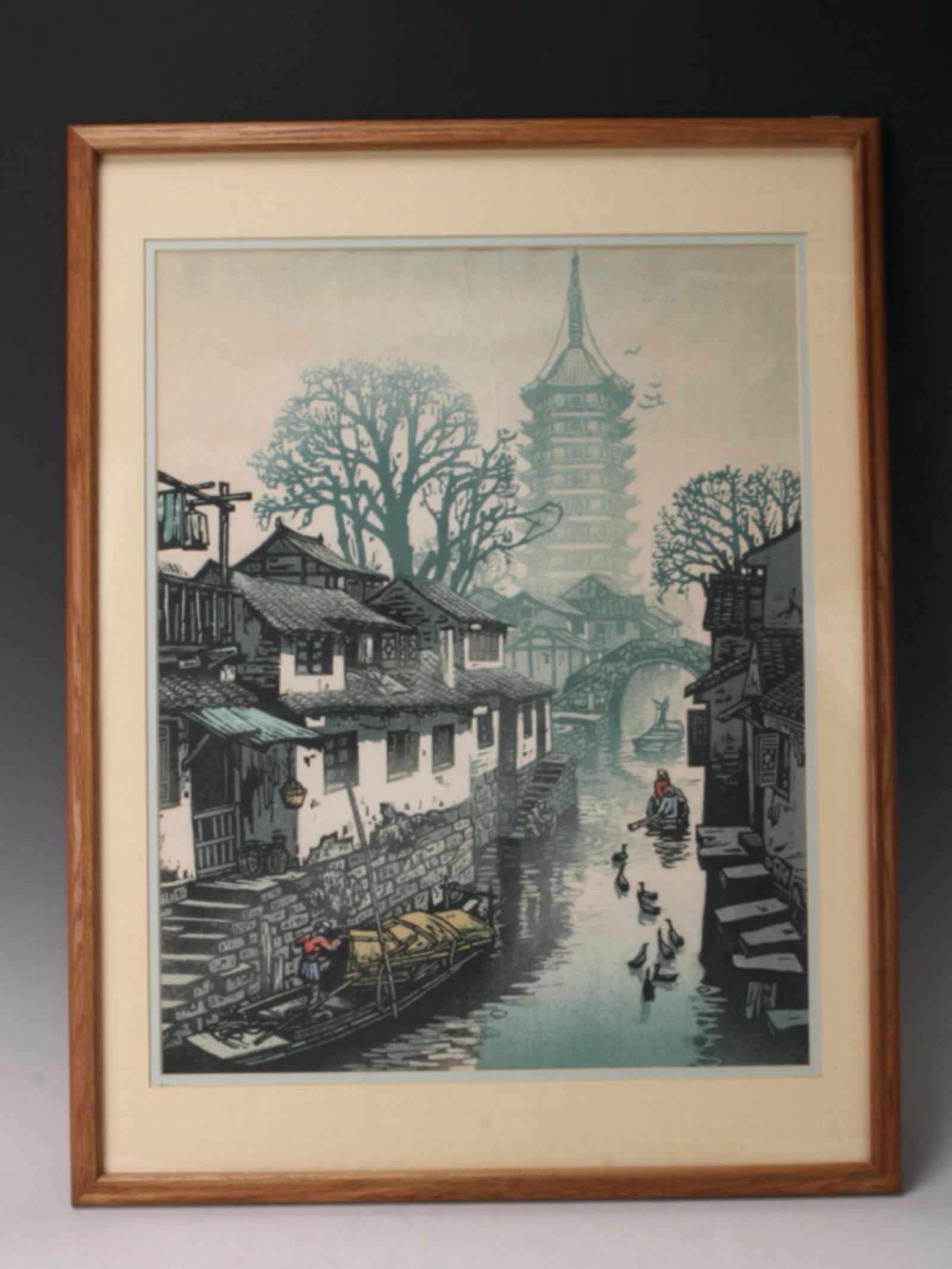 FRAMED ASIAN VILLAGE SCENE: Houses sit along a river with rafts and ducks floating by. Trees and a pagoda are off in the distance. 19" X 25" $40 - $80 Please contact us for high resolution images of this lot.
