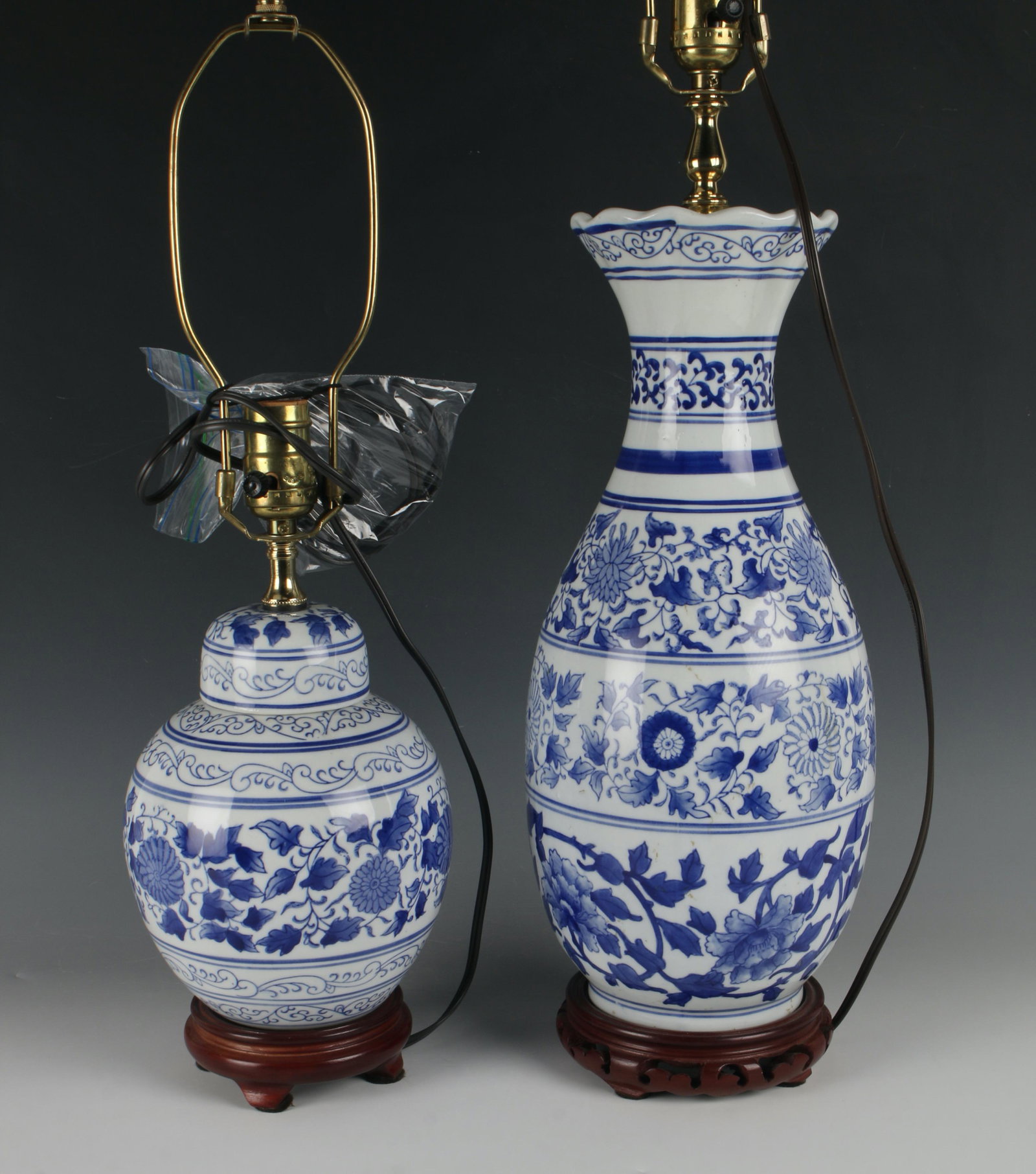 PAIR BLUE & WHITE LAMPS W BROCADE SHADES: One vase form and the other is a ginger jar, both on custom carved wooden stands. With floral and tendril designs. Brocade shades with floral designs. Includes harps and finials. 7" X 33"