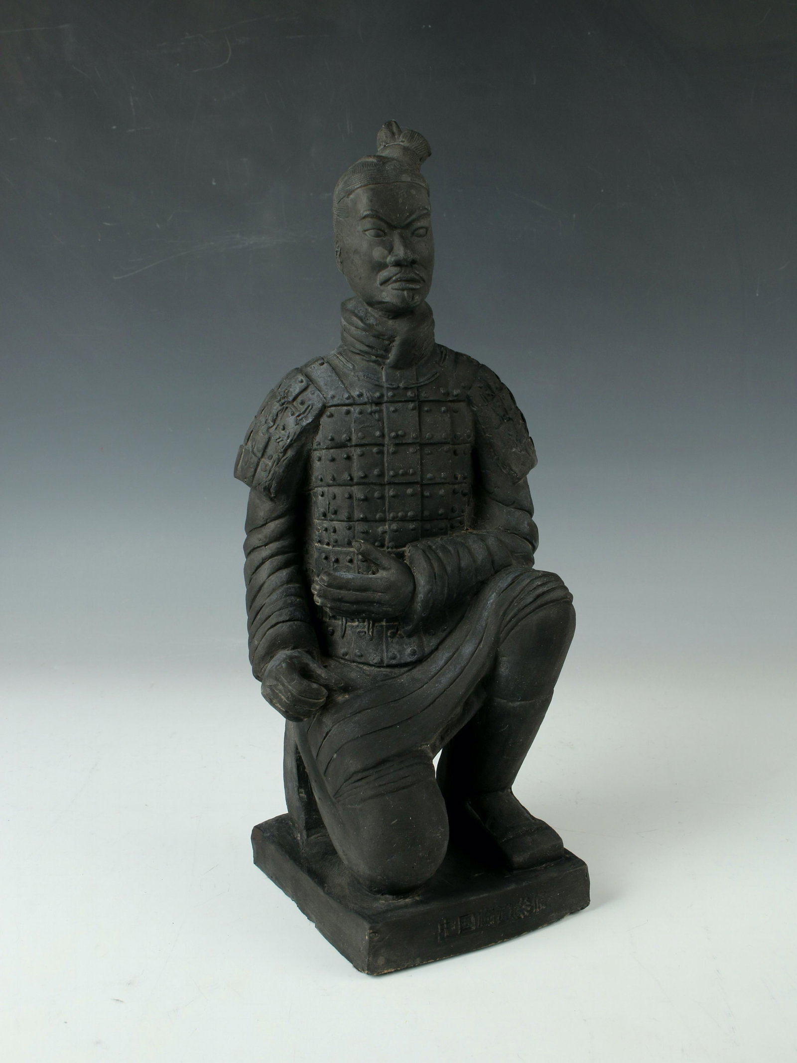 KNEELING WARRIOR FIGURE STATUE: Kneeling warrior in his armor in unglazed black. With incised and carved detail. Missing sword. 4 1/2" X 13 1/2" $40 - $80 Please contact us for high resolution images of this lot.
