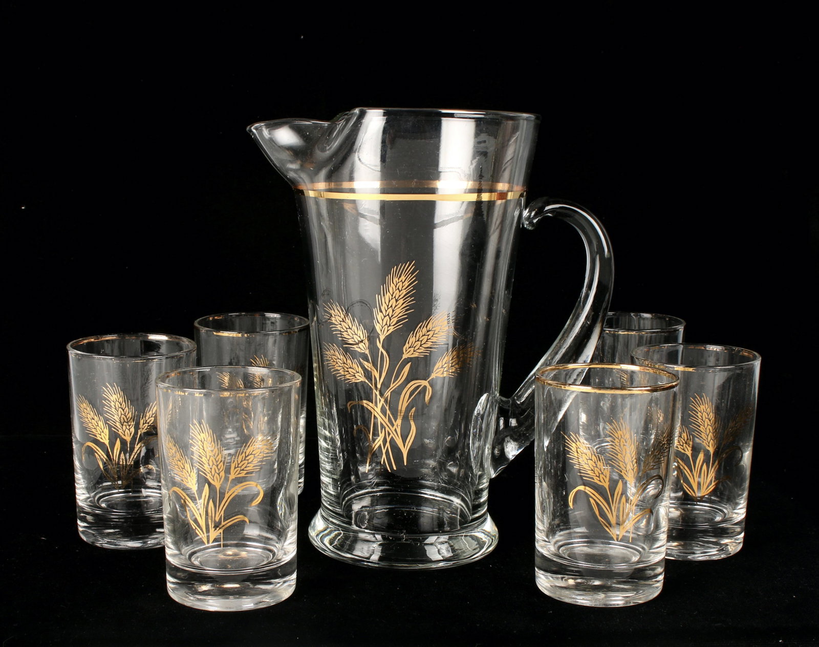 LOT OF ASSORTED GLASSWARE: Pitcher and six juice glasses Golden Wheat in original box West Virginia Glass Company. Some wear to gold on rims. Six demitasse cups, white with gold rim. Two shot glasses. 2 1/2" $40 - $80