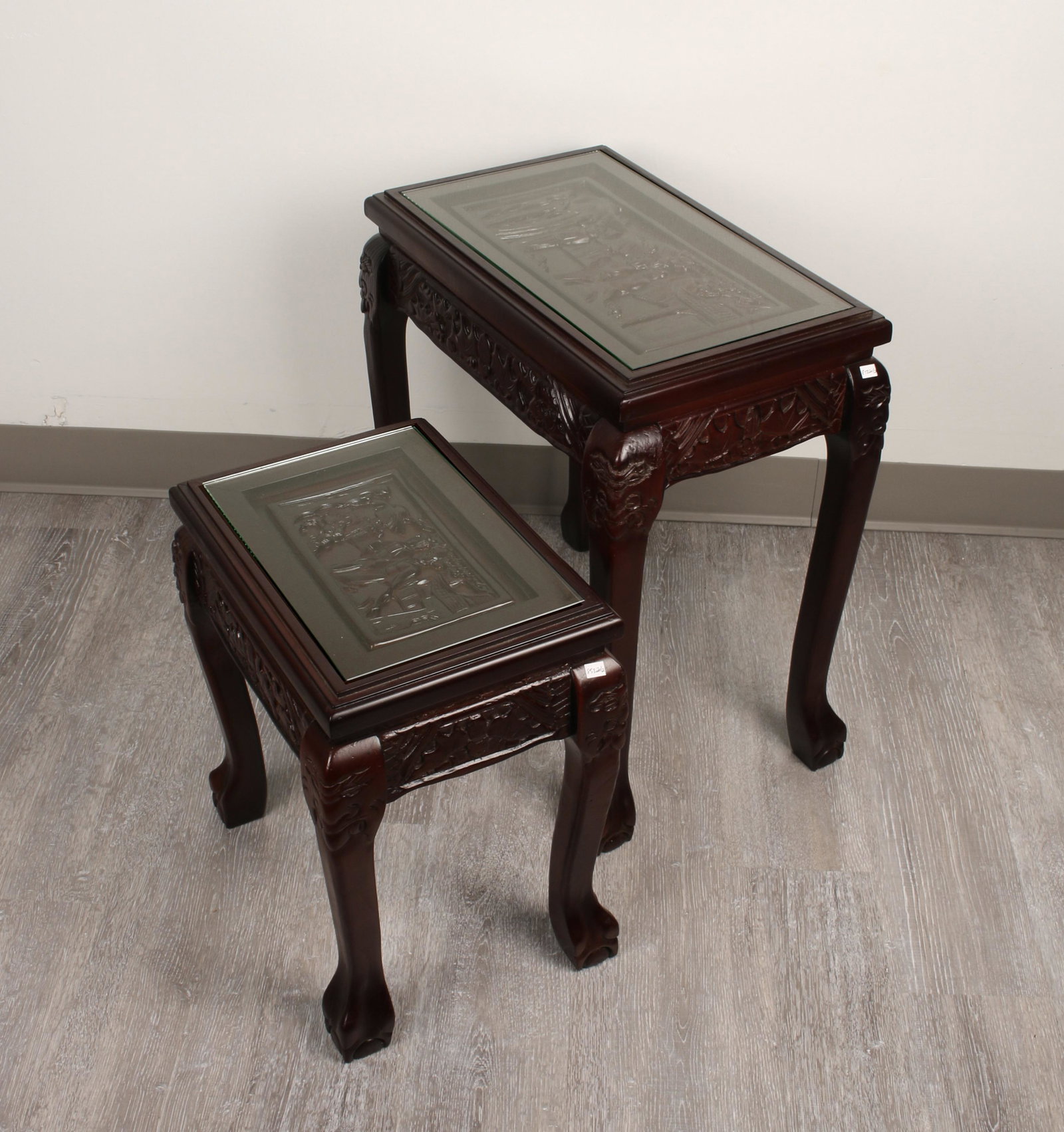 PAIR CARVED NESTING TABLES W GLASS TOP: Carved scenes on the top, and carved legs and feet. Glass tops. 19" X 21" $40 - $80 Please contact us for high resolution images of this lot. Shipping: W