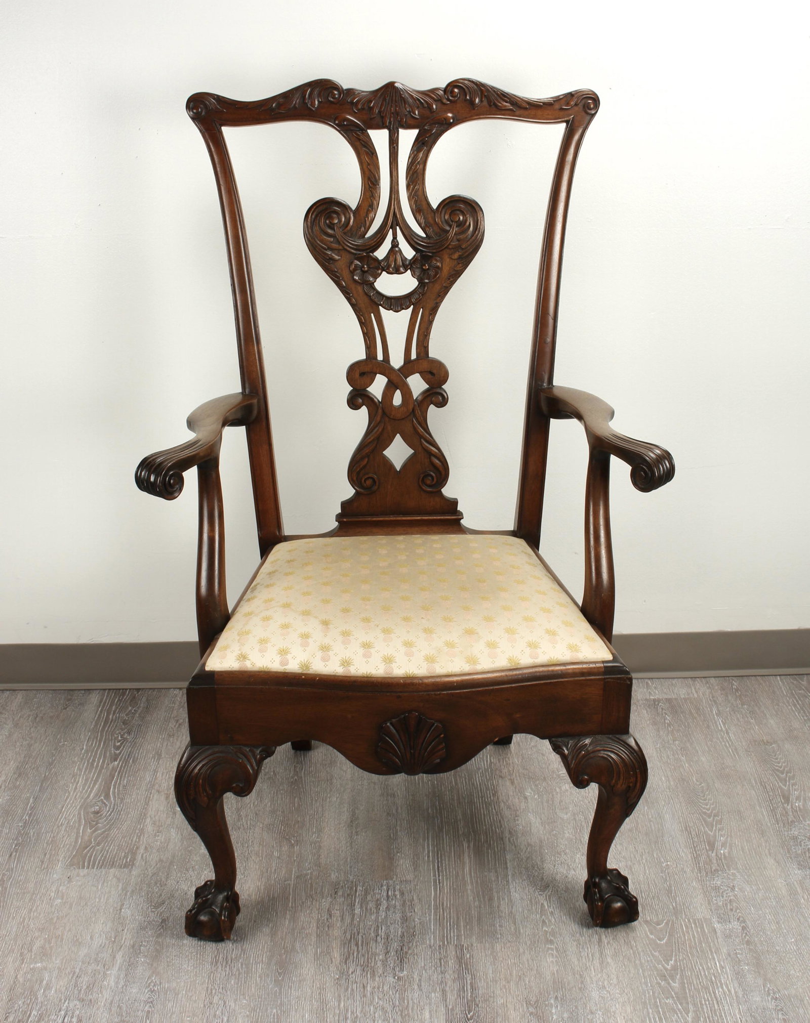 LARGE CHIPPENDALE STYLE CARVED ARMCHAIR: Elaborately carved backsplat in curvilinear designs. Scroll arms. On ball and claw feet. 47" x 25" x 23" $100 - $200 Please contact us for high resolution images of this lot.