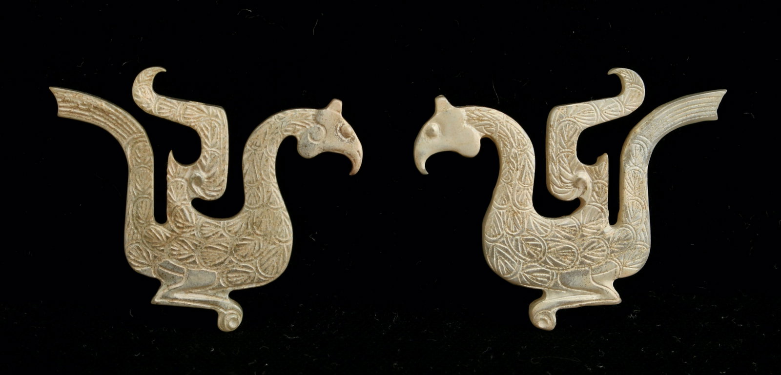 TWO PIECES OF WESTERN ZHOU JADE: Two small pieces of jade shaped in the form of archaic phoenixes. They have detailed feathers and tails. 34 mm X 44 mm X 4.4 mm $1000 - $1500 Please contact us for high resolution images of thi