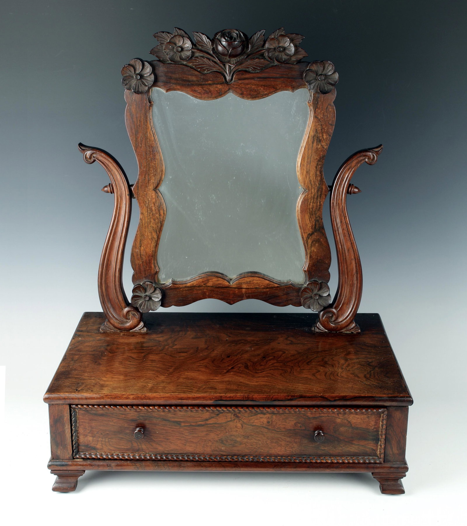 ANTIQUE CARVED SHAVING VANITY MIRROR: Highly grained wood, a center drawer with carved "rope" edging details, and roses and flowers carved in to the top of the mirror. Mirror is on a swivel. 18" X 12" X 22" $10