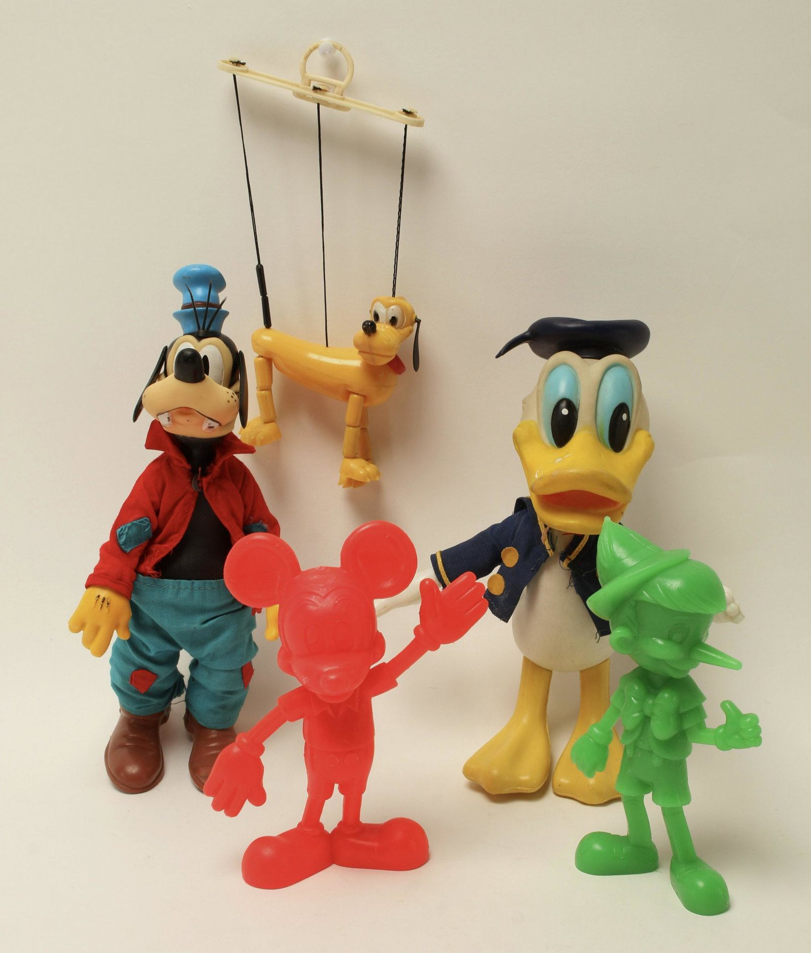 ASSORTED LOT PLASTIC DISNEY TOYS: Including Donald Duck made in Hong Kong, Pluto marionette made in Hong Kong, red Mickey Mouse made in USA, Goofy made in Hong Kong, and green Pinocchio made in USA. 8 1/2" $40 - $80 Pleas