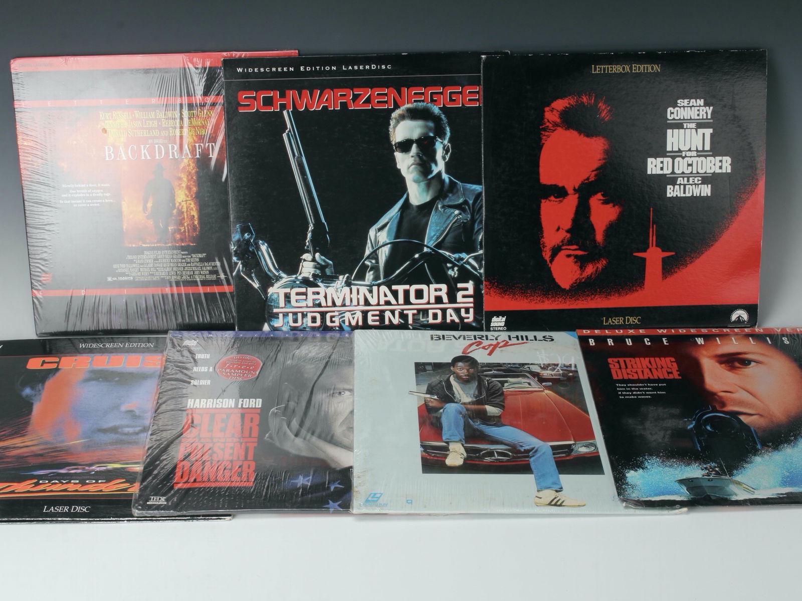 VINTAGE MOVIE LASERDISCS: Vintage laserdisc lot. Includes Backdraft, Terminator 2, The Hunt for Red October, Striking Distance, Beverly Hills Cop, Clear and Present Danger, and Days of Thunder. 12 1/2" x 12 1/2" $