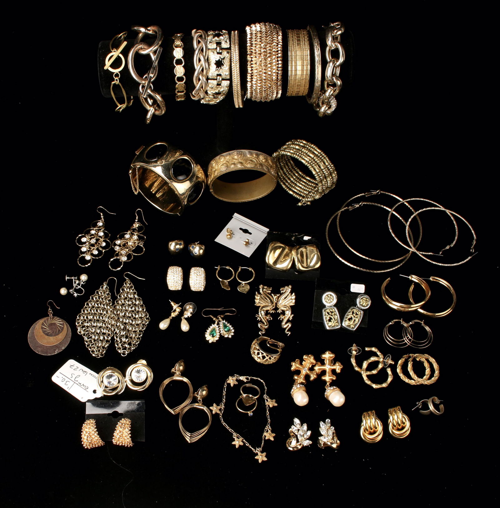 LARGE LOT VINTAGE GOLD COSTUME JEWELRY: Vintage bracelets and earrings in gold tone. Some rhinestone, Heavy chain bracelets, cuffs, drop earrings, hoops and more! Provenance: Major NYC fashion and antiques collector. Primarily collected in