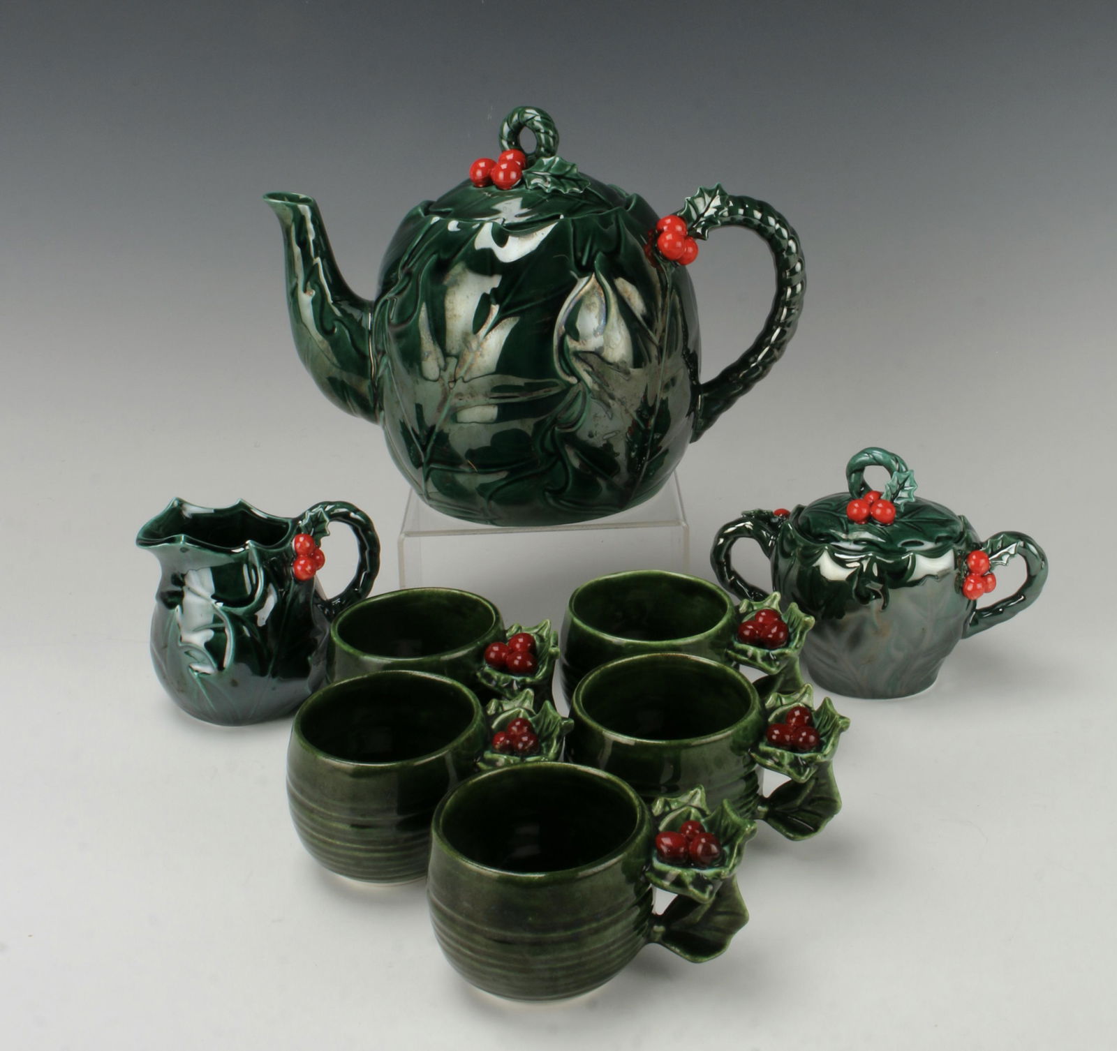 VINTAGE LEFTON CHRISTMAS GREEN HOLLY TEA SET: Five cups with holly berry and leaf handles. Tea pot, sugar, and creamer are marked Lefton. Sticker is off of tea pot but style number 1357 is on it. Sugar and creamer marked 1355 and still have stick