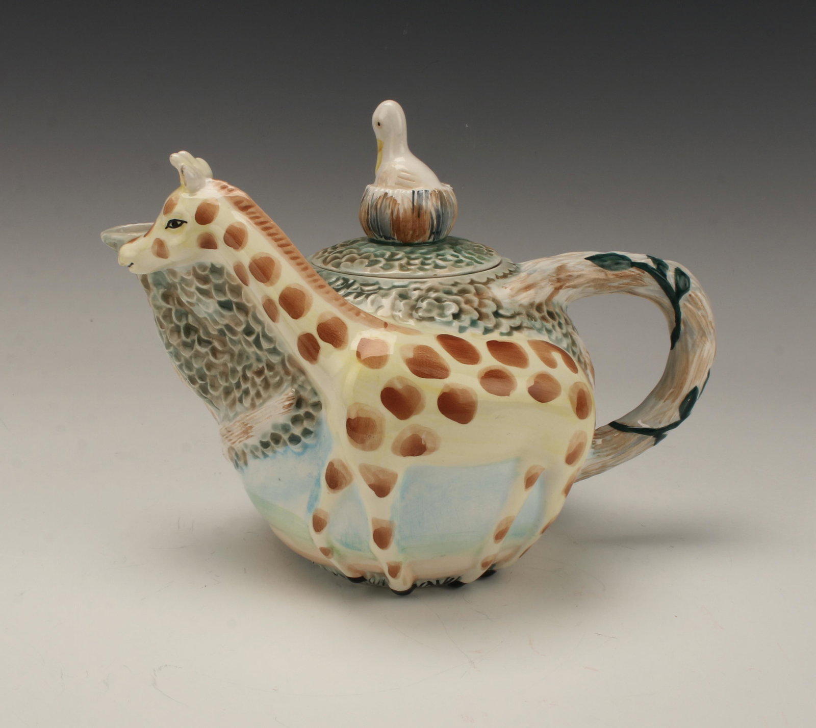 VINTAGE STRATA GROUP JUNGLE SPREE CERAMIC GIRAFFE TEA: Charming tea pot decorated with a giraffe along one side of the body spanning the spout to handle. The body of the tea pot has savannah-like trees and foliage. The lid has a nesting bird finial. Marke