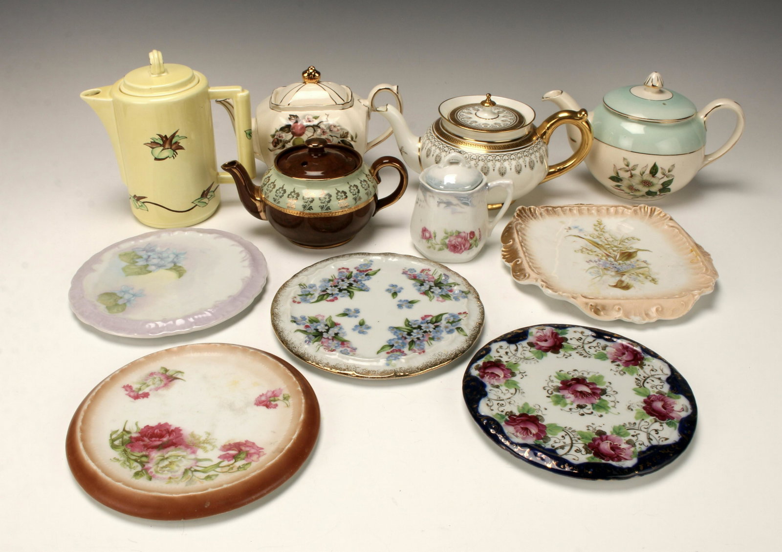 PORCELAIN TEA POTS AND TRIVETS: German trivets, English and German teapots, and a sterling Bermuda souvenir spoon. 7" $100 - $200 Please contact us for high resolution images of this lot. Shipping: