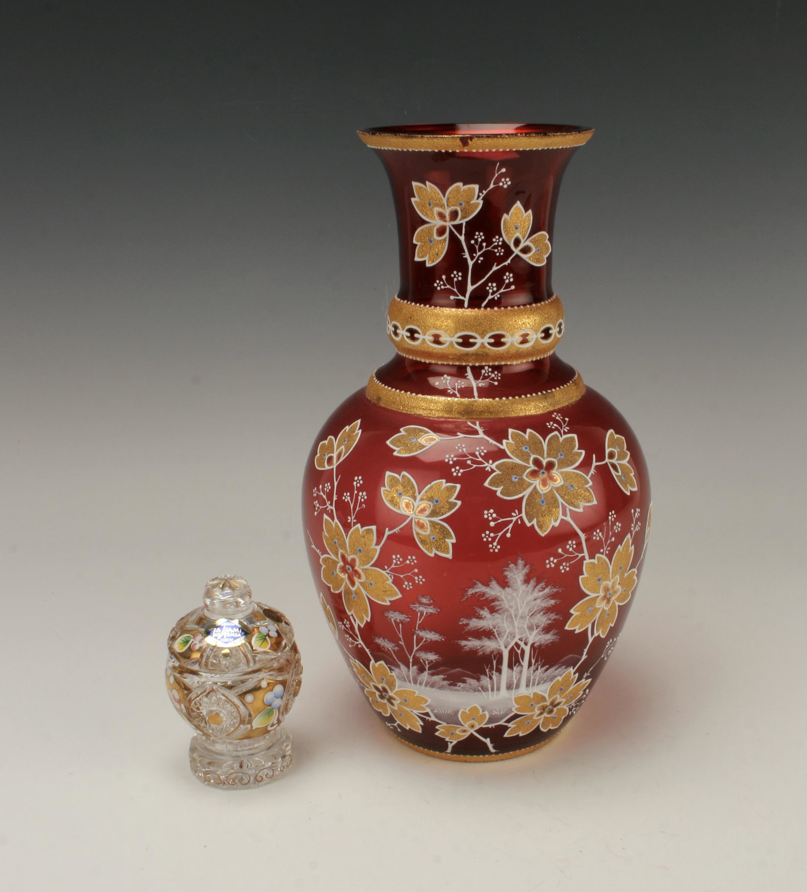 CZECH CRYSTAL JAR & CRANBERRY GLASS VASE: Hand cut Czech Crystal Jahama Bohemia jar with gold overlay and hand painting. Cranberry glass vase with gilt overlay and hand painting of winter forest and colorful flowers. 6" X 11"