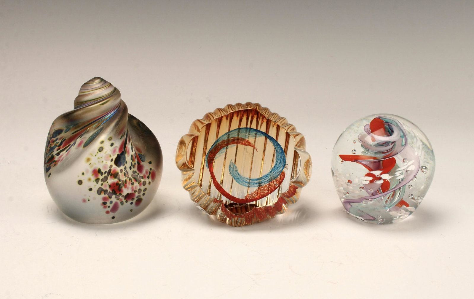 3 SIGNED ART GLASS PAPERWEIGHTS: The clear glass with external ridges and central swirl is signed Caithness Art Glass Paperweight, Ocean Collection Sea Pearls, Scotland. The frosted glass shell form with multicolor luminous dots is s
