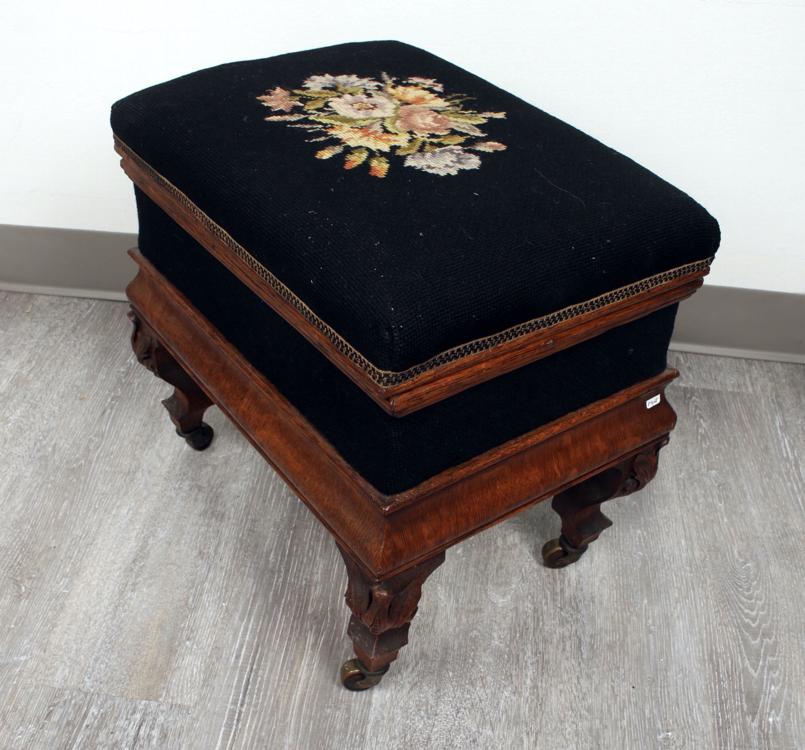 VICTORIAN QUARTER SAWN OAK HINGED FOOT STOOL: With hand needlepointed stop and sides. Carved knees, legs on bronze casters. Quarter sawn oak. With hinged lid that opens to reveal storage compartment. 18" X 12" X 16" $100 - $200<