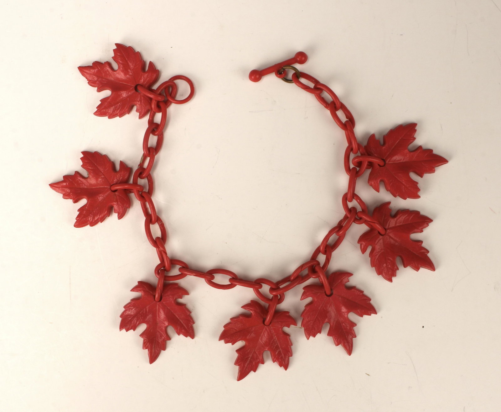 BAKELITE MAPLE LEAF BRACELET: Seven maple leaves hang from loop chain with toggle clasp. 8" $40 - $80 Please contact us for high resolution images of this lot. Shipping: We are able to pack