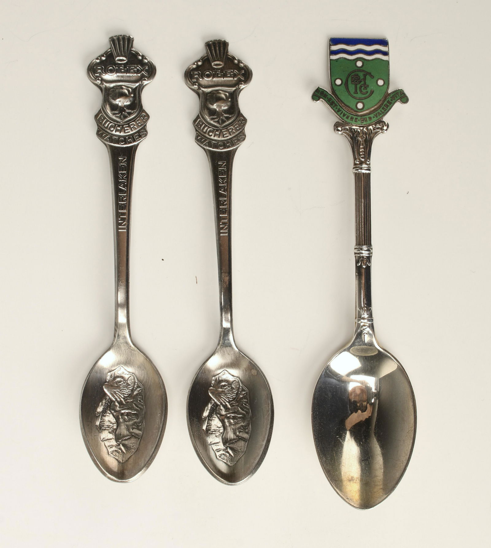 3 SOUVENIR SPOONS 2 ROLEX SILVER PLATED SPOONS: Two spoons say Rolex Bucherer Watches, Interleken at the top. The other is Bach & Co. with hallmarks. Enamel top with a Latin saying. 4 1/2" $40 - $80 Please contact us for high resolut