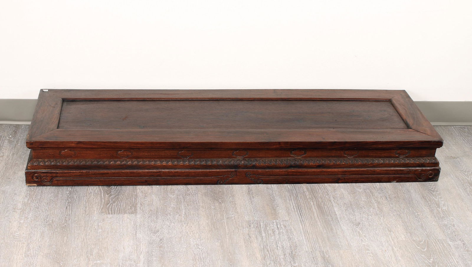 DRAGON DECORATED ALTAR TABLE RISER: A Huanghuali altar table riser with striking grain, inset panel top, and carved on three sides with a ruyi border. The bottom is carved in facing dragons. 52 1/2" X 16 3/4" X 6" $100