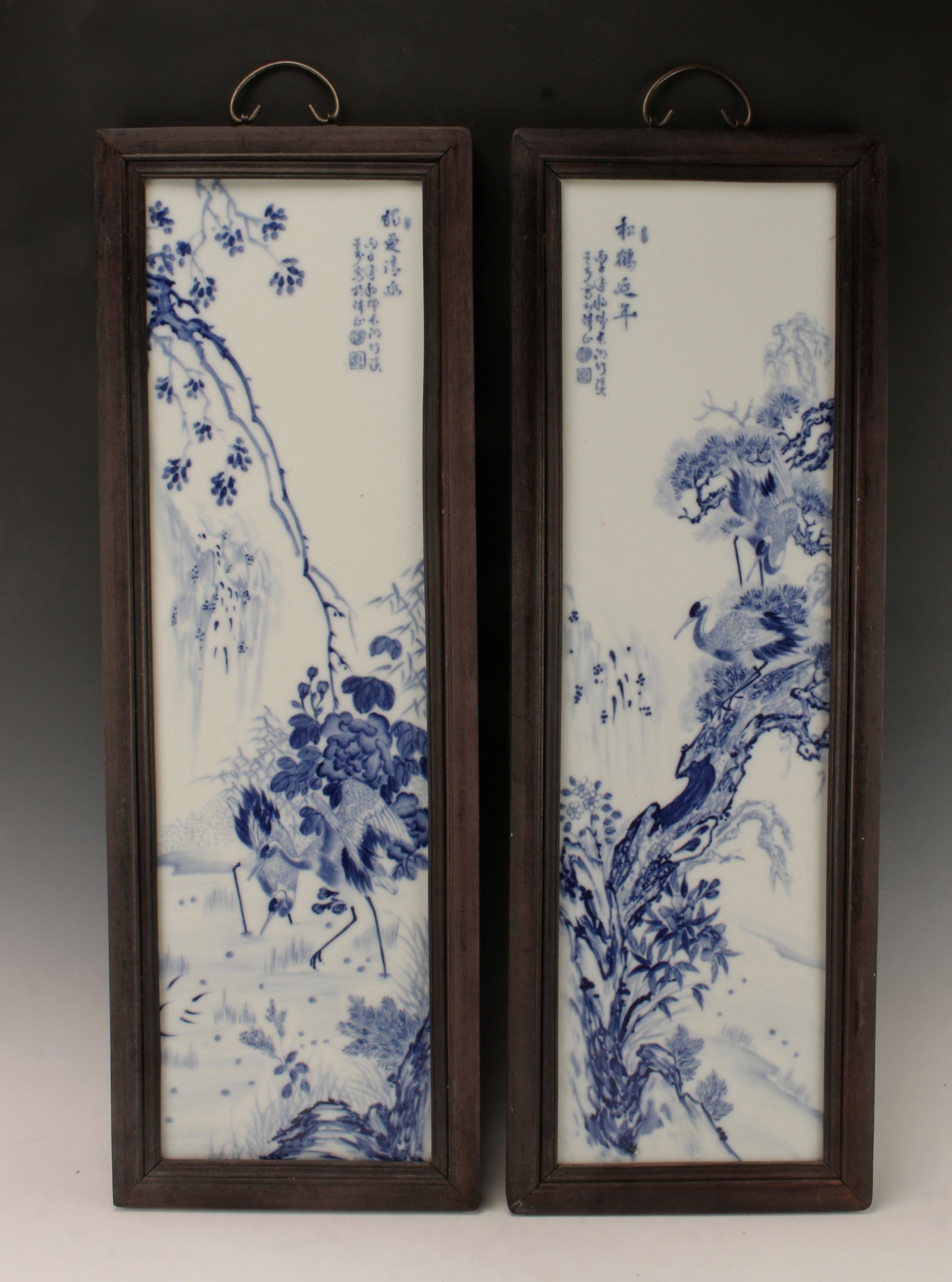 PAIR WANG BU BLUE & WHITE PORCELAIN PLAQUES: Two blue and white plaques of a pair of cranes by the waterside under flowering branches. Calligraphy and artist marks on right. Framed and with hardware for hanging. 11" X 32" $200 - $40