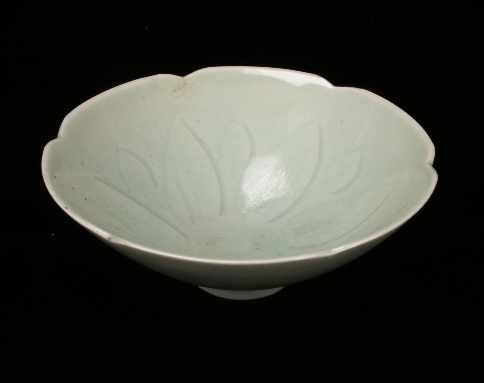 CHINESE CELADON LOTUS BOWL: Incised with petals in the interior the rim is shaped in petal forms. In pale celadon with details revealed by the pooled glaze. 5 1/4" X 2" $100 - $200 Please contact us for high reso