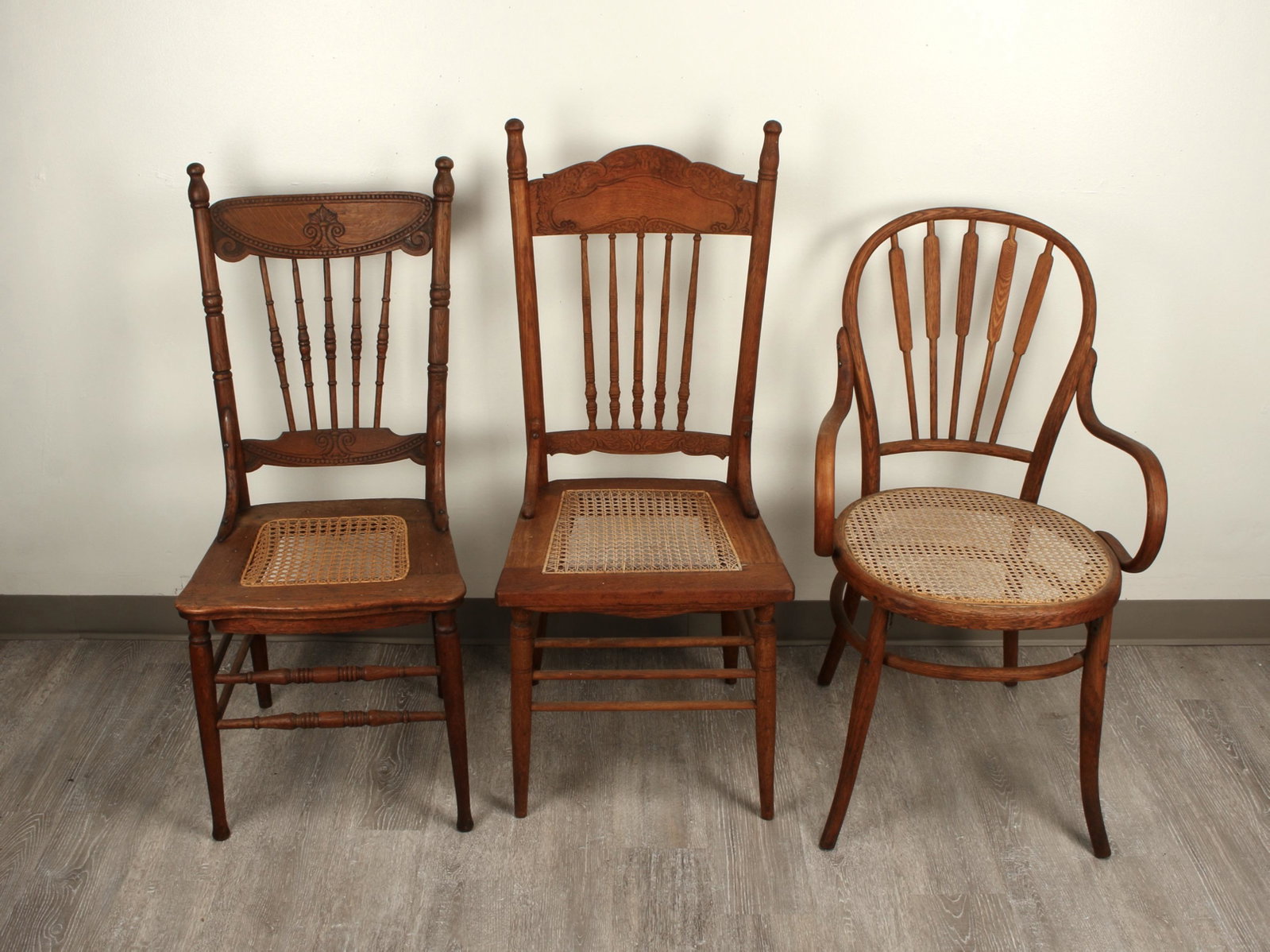 3 OAK CHAIRS CANE SEATS: All three have cane seats. All seats are in good shape. The two pressed back seats have spindle backs. One bentwood chair with curved arms and radiating five spoke back. 17 1/2" X 16" X 41 1
