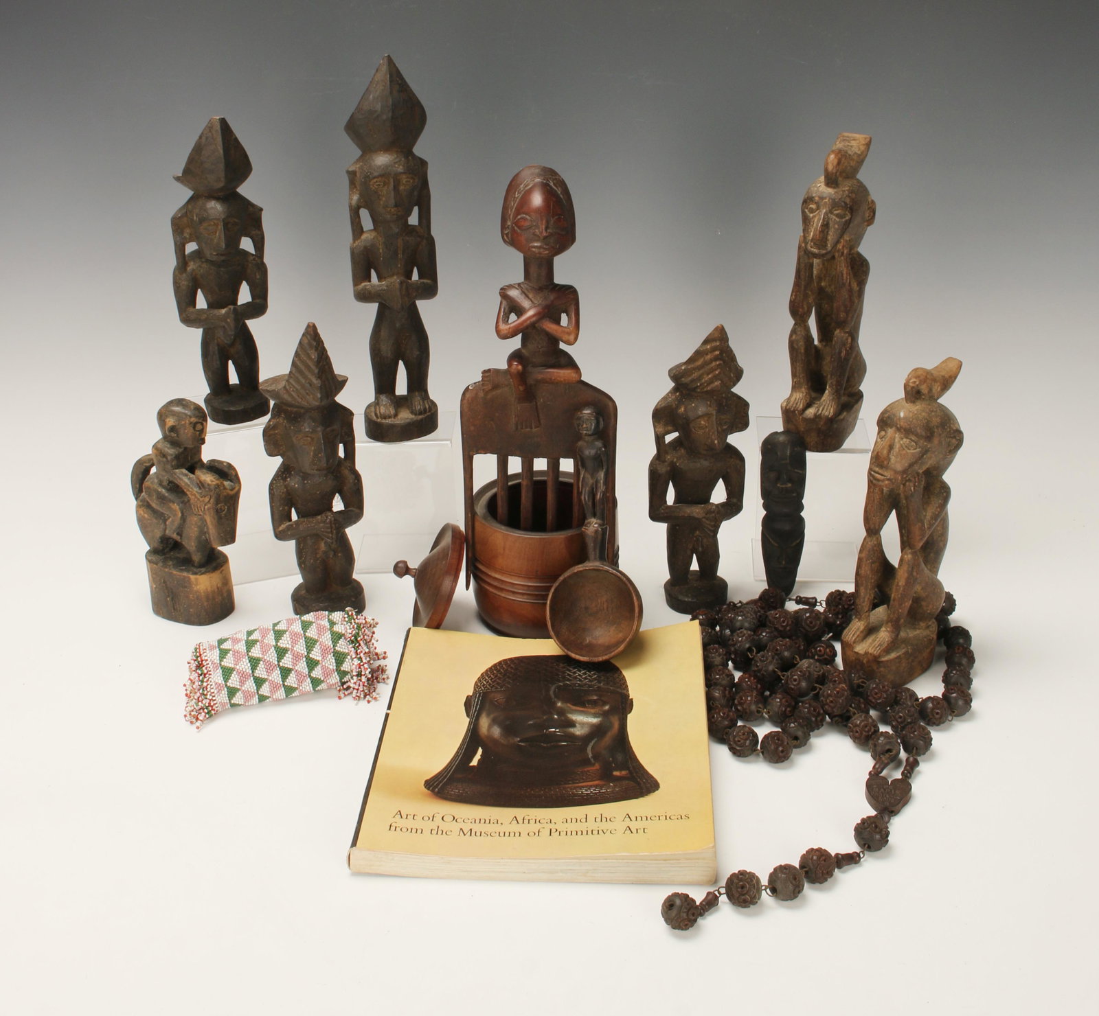LARGE LOT OF AFRICAN FIGURES & ARTIFACTS: Seven carved wooden figures, figural ladle, figural comb, small carved wooden totem. Turned wooden lidded container, pierced wooden rosary, small beaded container. Art of Oceania, Books: African, and 