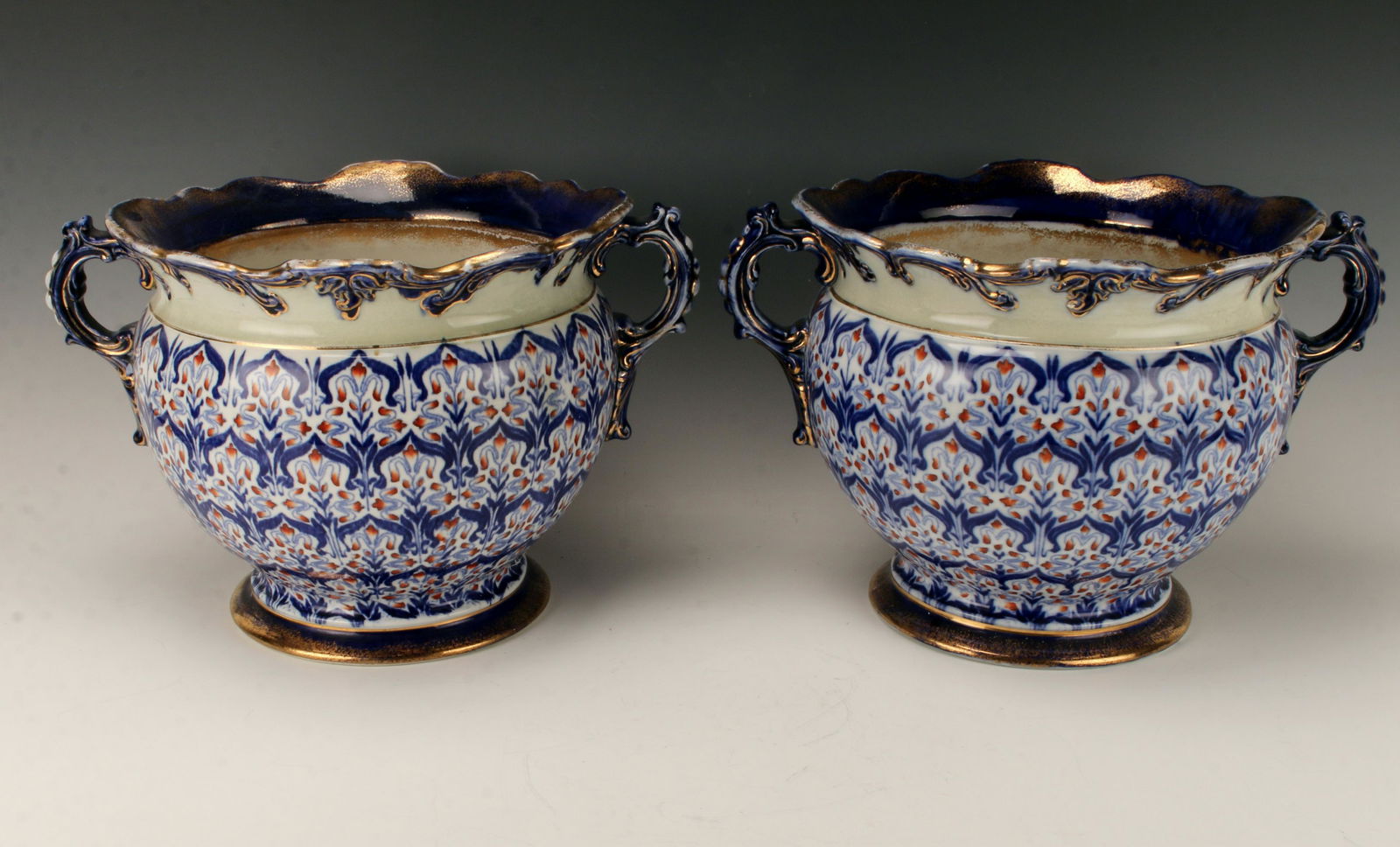 PAIR ANTIQUE FLOW BLUE HANDLED PLANTERS: In William Morris style floral border design with orange flowers. In classic flow blue with abundant gold accents. Marked B50 on bottom. 15" X 10" $100 - $200 Please contact us for hi