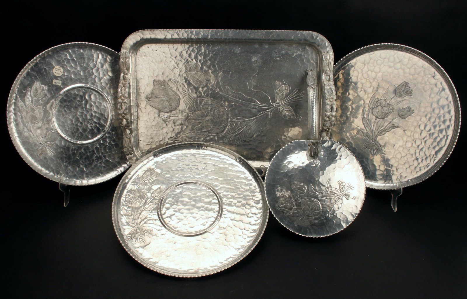 RODNEY KENT HAMMERED ALUMINUM TRAYS CRUMBER: 3 circular trays, a rectangular tray, and a hinged crumber, all in tulip pattern hand forged by Rodney Kent. 16 1/2" x 11 1/2" $100 - $200 Please contact us for high resolution images