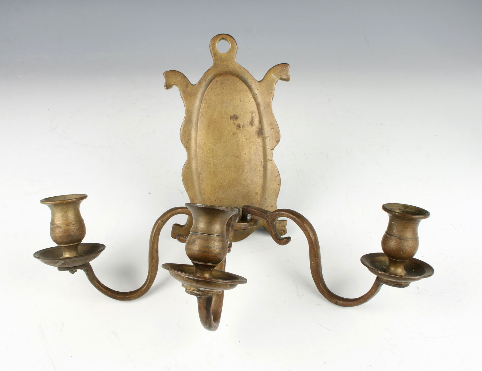 ANTIQUE THRIPLE BRASS WALL SCONCE: Antique cast brass wall sconce with convex oval back design. Three removable candle arms. 8" $40 - $80 Please contact us for high resolution images of this lot. Shipping: