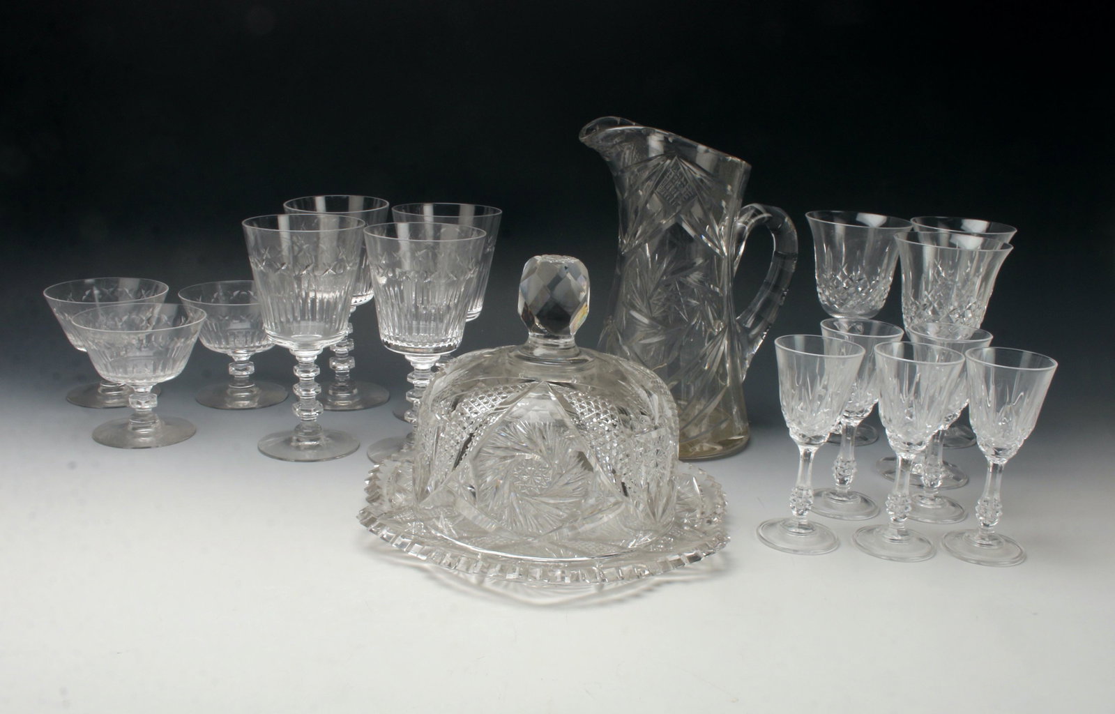 LARGE LOT CUT CRYSTAL & GLASS GLASSES: Cut crystal covered cheese plate and pitcher. 4 water glasses, 3 sherbet glasses, 5 cordials, and 3 wine glasses. 9 1/4" $20 - $40 Please contact us for high resolution images of this lot.