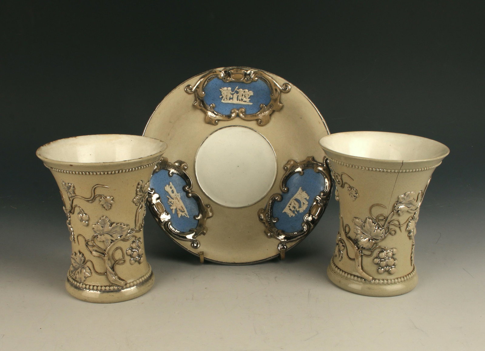 EUROPEAN SILVER & GRAY BISQUE VASES AND PLATE: Unusual antique European gray bisque ware accented with metallic silver Rococco flourishes on floral decoration. The vases or cups have three-dimensional plaques on the bottom with the number "10