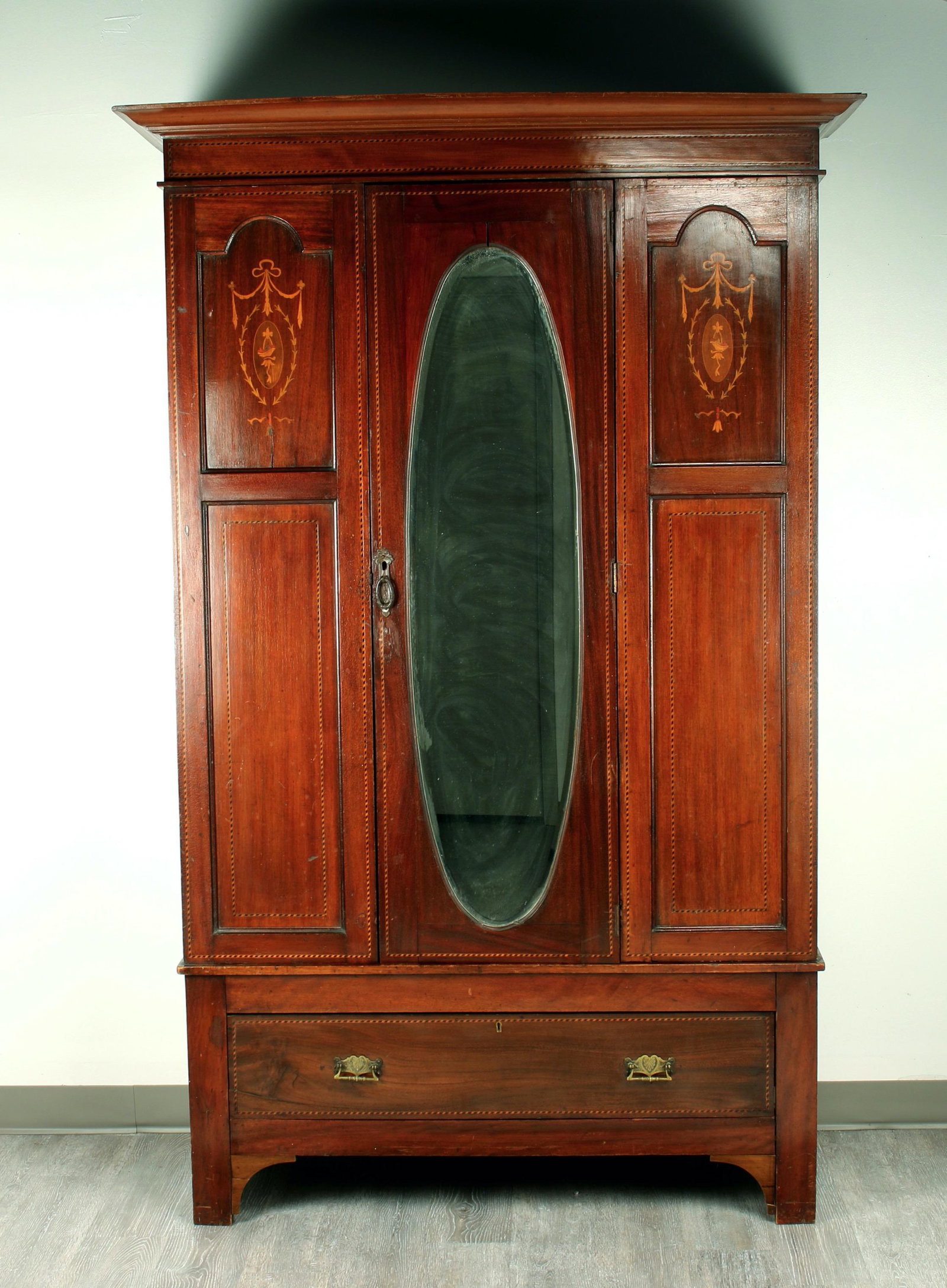 EDWARDIAN STYLE SINGLE DOOR WARDROBE ARMOIRE: With mixed wood marquetry front panels and fine stringing details. Brass hardware and interior fittings, on drawer, in base, and brass ring pull. Bracket feet. Front panel inlay is a garland and baske