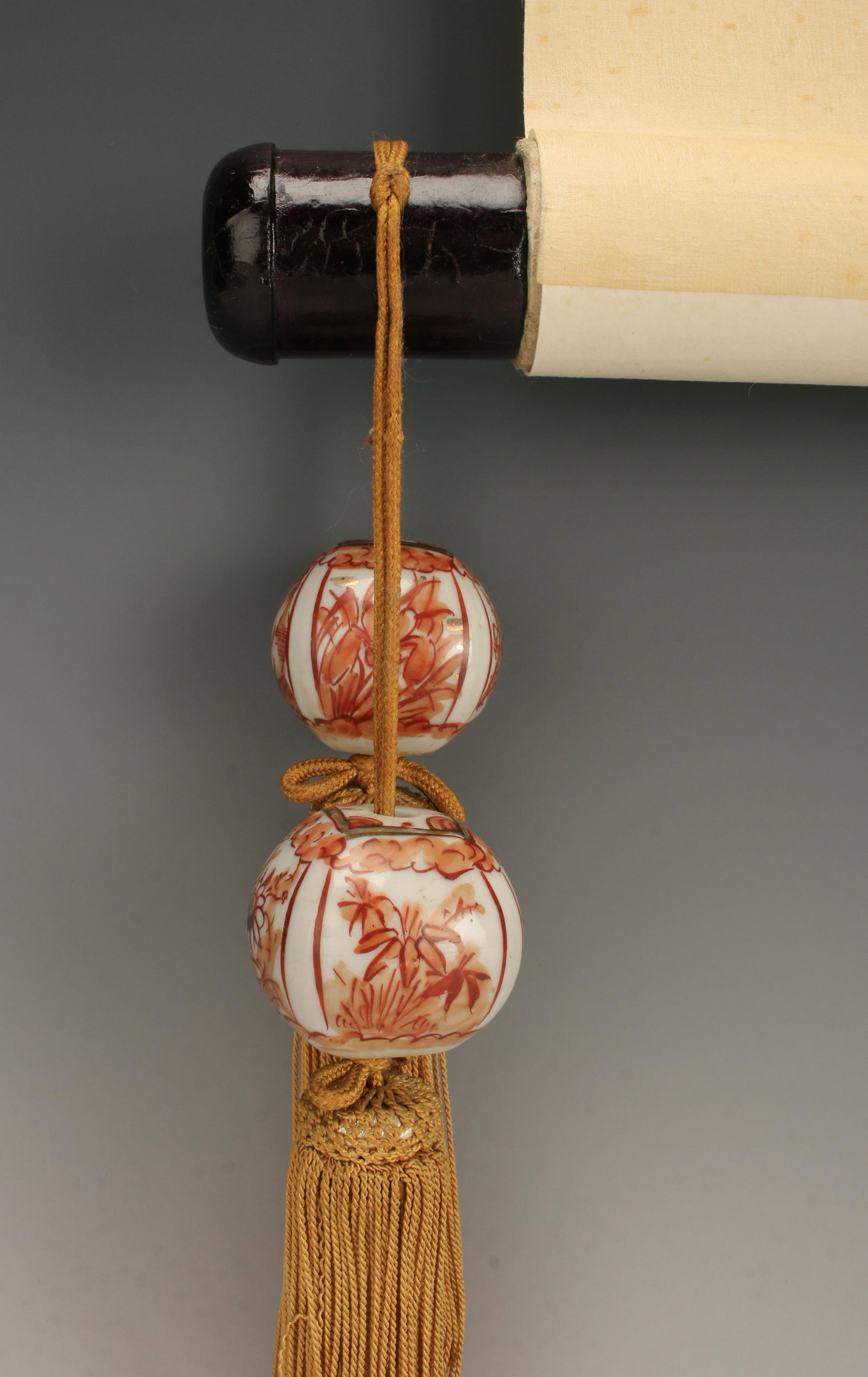 PAIR PORCELAIN HANGING SCROLL WEIGHTS: In vermillion color and gold accents glaze on white with garden scene floral designs, and graphic patterns. Attached gold colored cords and tassels. Scroll not included. Bead: 1 1/2" $100 - $20