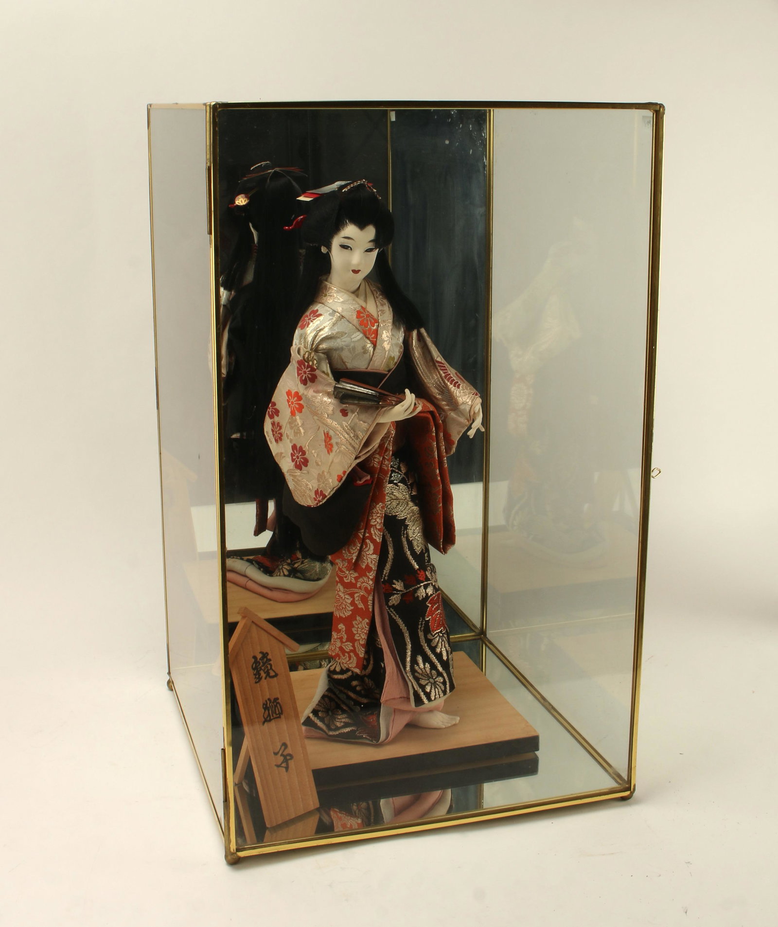 GEISHA DOLL IN MIRRORED GLASS CASE: Painted face. The bottom and back of the case are mirrored glass to reflect her costume. 12" X 12 1/2" X 20" $40 - $80 Please contact us for high resolution images of this lot. <
