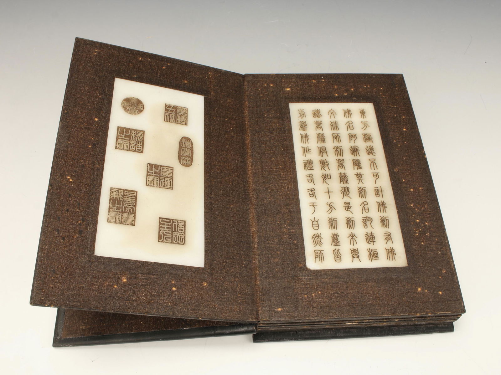 ANTIQUE TIBETAN BOOK WITH JADE PAGES: 8 pages of panels with incised white jade calligraphy set in brown fabric frames. Covers are carved with dragons and clouds. 9" x 5 3/4" x 1 3/4" $400 - $600 Please contact us fo