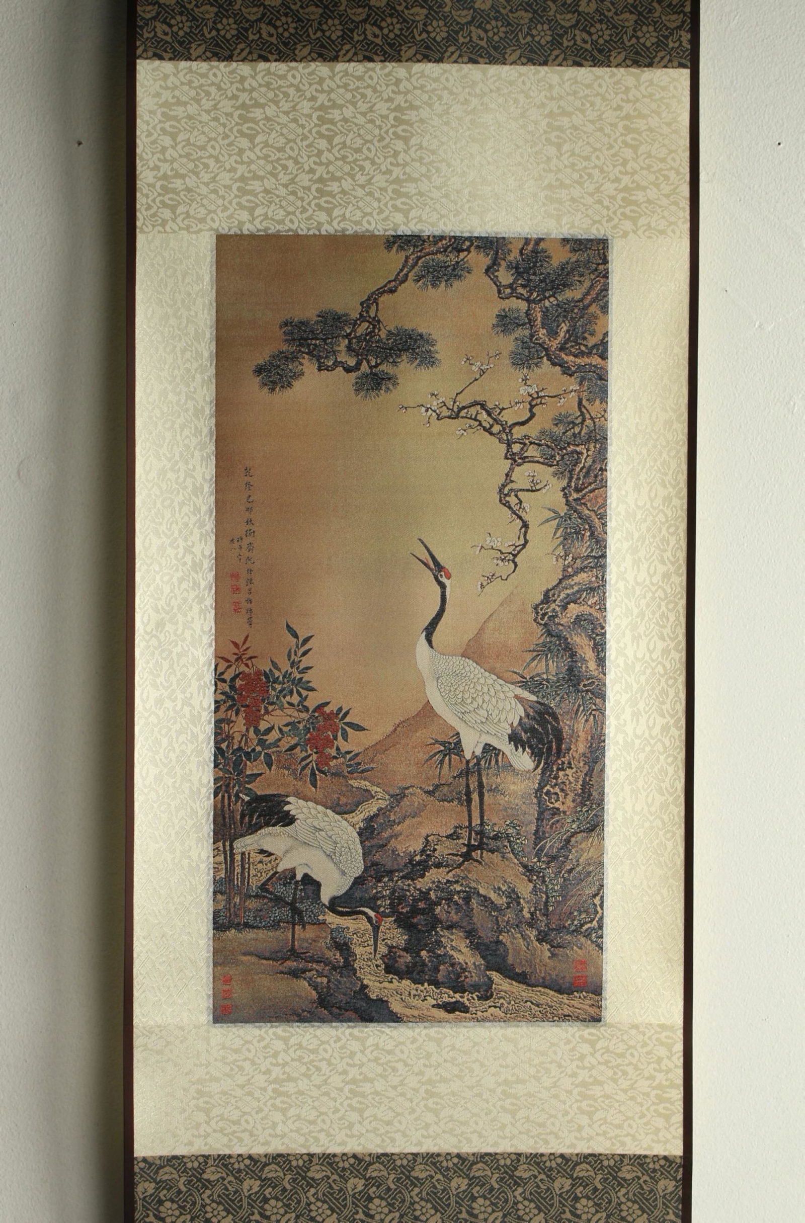 WOVEN SCROLL OF CRANES IN PRESENTATION BOX: Silk tapestry with woven scene of two cranes in a garden. Calligraphy and artist marks on left and bottom right. Design is based on Crans with Pine and Plum Blossom by Shen Quan (ac. 1682 - 1762, Qing