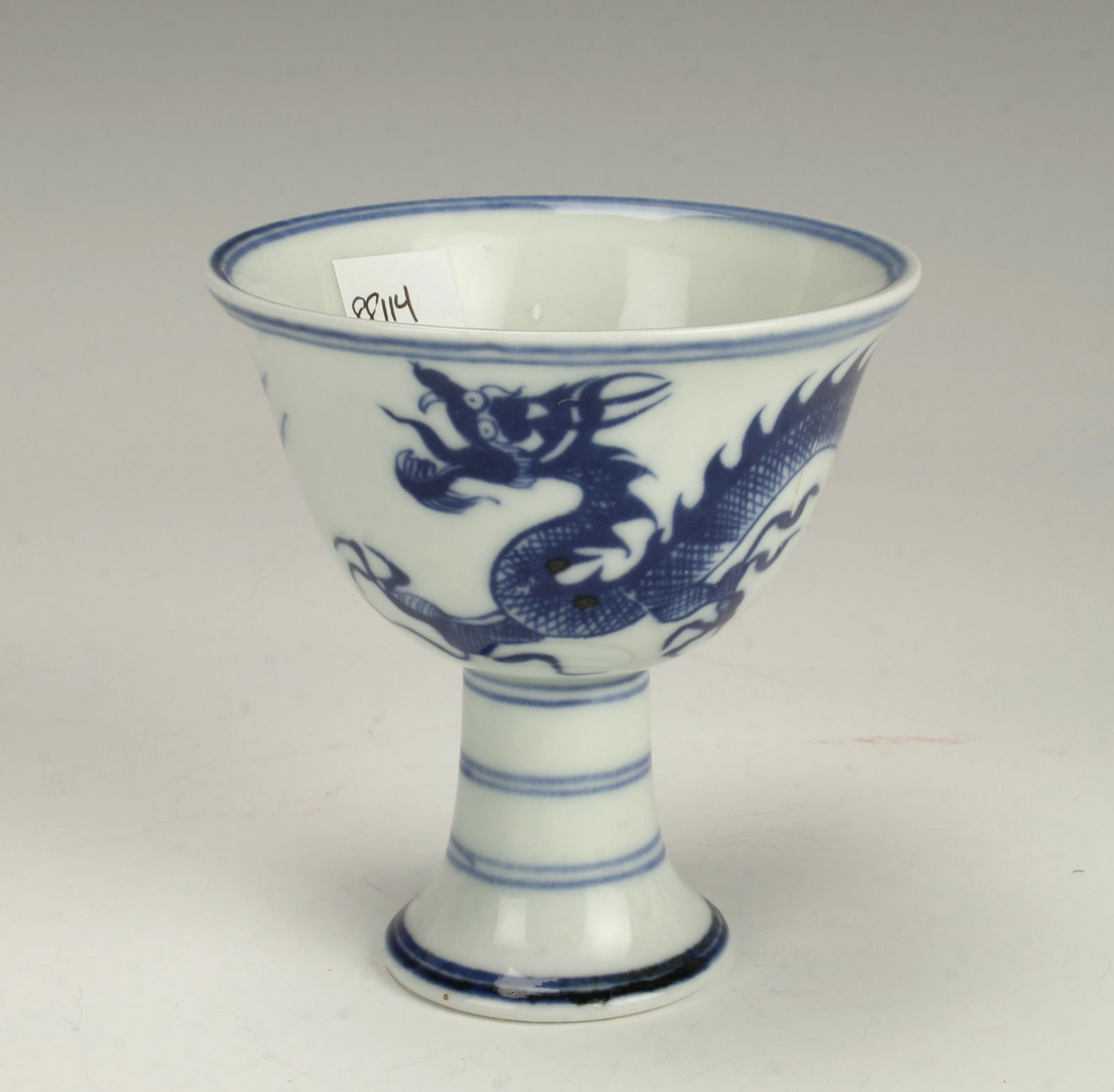 BLUE & WHITE HIGH HEELED DRAGON CUP: A dragon swirls around the body of the cup chasing a flaming pearl. Marked on the inside of the heel. 3 1/4" X 3 1/2" $100 - $200 Please contact us for high resolution images of this