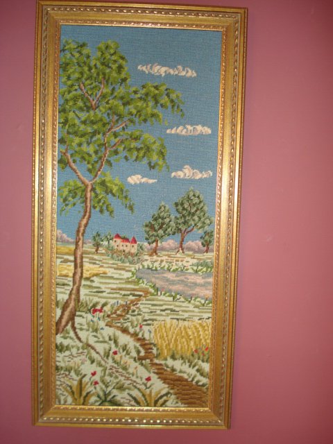 Needlepoint: A framed 20th C. needlepoint showing a rural landscape with a mansion. 35 1/2" X 17".