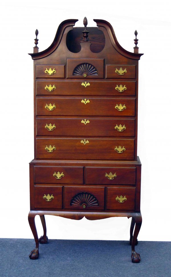 Mahogany Chippendale style Highboy: A Chippendale style solid mahogany scrolled pediment closed bonnet highboy featuring carved ball and claw cabroile legs, and a base supporting a top with five drawers, and three flame finials. Overall