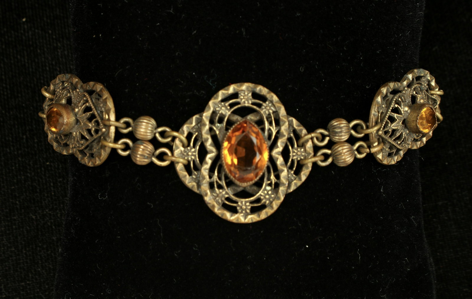 VICTORIAN REVIVAL BRACELET: Filigree links are bezel set with amber colored faceted stones and joined by fluted ball beads. 7 1/2" $40 - $80 Please contact us for high resolution images of this lot. Shipping:</