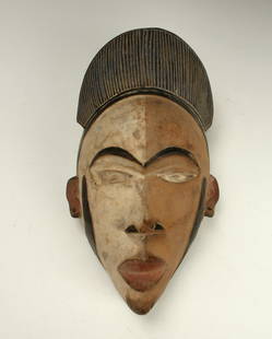 YOMBE CONGO MASK: Yombe Congo MaskBlack headdress with incised verticals. The face is half brown, half white. Black