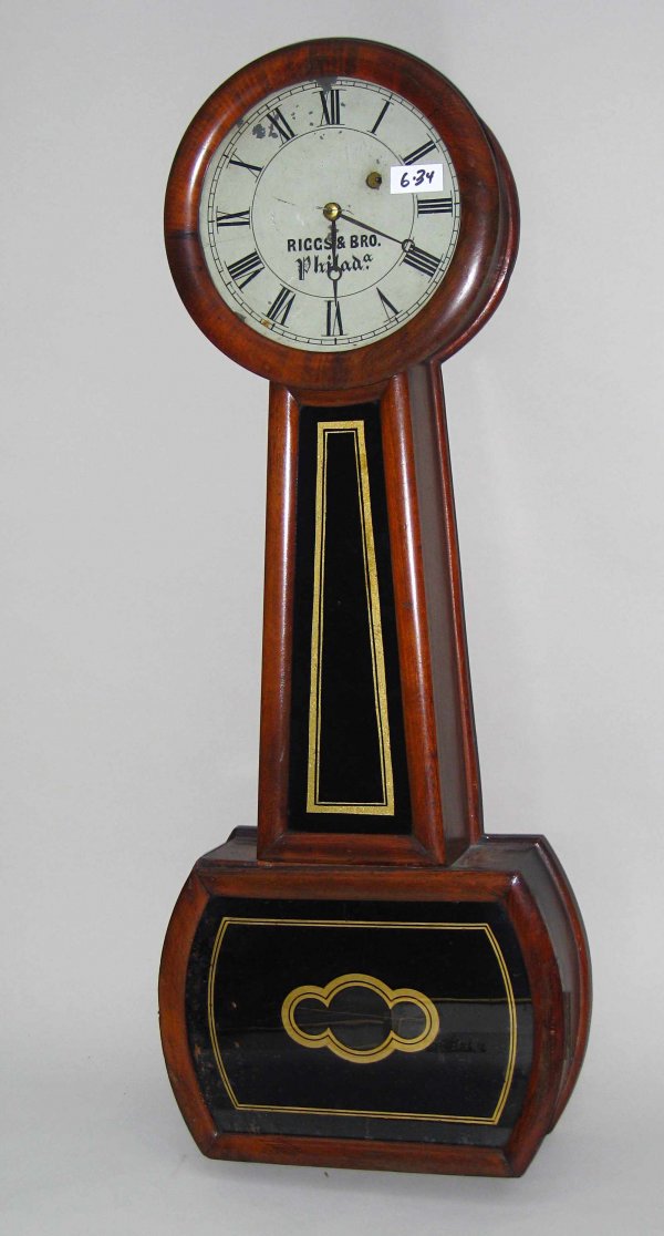 Riggs & Bros Banjo timepiece by Howard: A weight driven mid 19th century banjo timepiece within a rosewood decorated case, reverse painted glasses and bowed pendulum box whose dial is signed "Riggs & Bros., Phila". Riggs Brothers was a larg