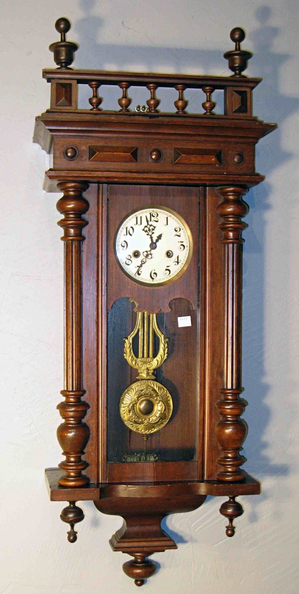 Gustav Becker wall clock : A walnut wall clock with original cresting with a strike mechanism, stamped on the back plate Gustav Becker, about 30" in overall height.