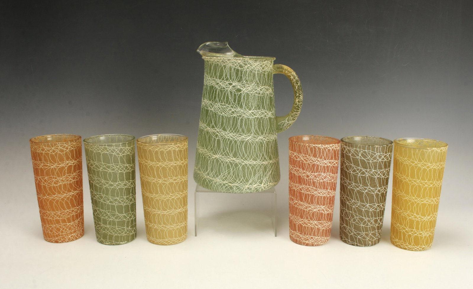 VINTAGE SPAGHETTI STRING PITCHER & 6 GLASSES: VINTAGE SPAGHETTI STRING PITCHER & 6 GLASSESReady for summer sangria! With green pitcher, 4 green glasses, and 2 yellow glasses, all with white "string" decoration.