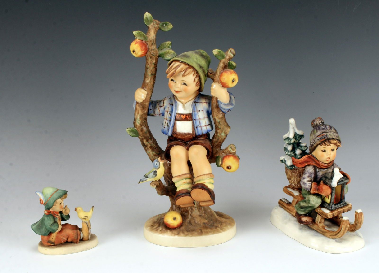 3 HUMMEL GOEBEL WEST GERMANY FIGURINES: 3 HUMMEL GOEBEL WEST GERMANY FIGURINES Smallest one is a little boy with a bird marked 63 and 50. Next is a boy sledding marked 396 1971. Largest is Apple Tree Boy sitting on tree branc