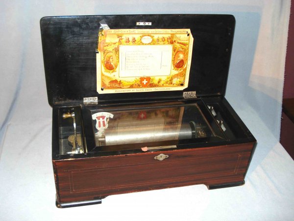 Music Box : A 19th century Swiss cylinder music box playing tunes: "Coming through the Rye"; Old folks at Home"; "Listen to the Mockingbird"; "Home Sweet Home". The faux painted and inlay case in good condition a