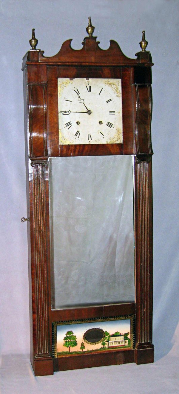 Ives Looking Glass Clock: A 56" mahogany, mirror and reverse painted cased wall clock by Ives. This with an iron painted dial above a mirror measuring 23 1/2" X 13 1/2" all above a reverse painted pendulum lentical. The case w