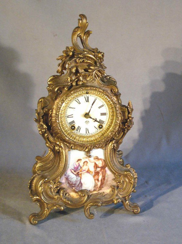 Ansonia Mantel Clock: A late 19th or early 20th century American mantel clock by Ansonia in the Louis XV French style, featuring a inset porcelain panel in multi-colors, cast gilded case.