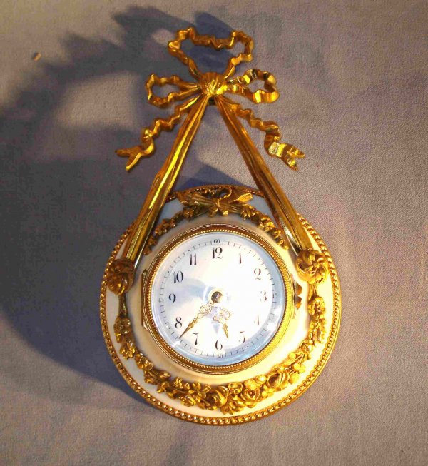 Wall Timepiece: A fine late 19th or early 20th Century French made wall timepiece of cast ormolu mounted onto a white marble base, 8" in height.