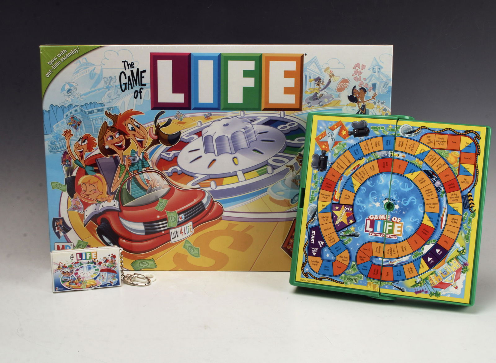 3 SIZES THE GAME OF LIFE LOT MINI TO FULL: 3 SIZES THE GAME OF LIFE LOT MINI TO FULL One keychain size game that opens to show board and one car. Marked 1998 Hasbro. One travel size game with compartment inside that holds wheel,