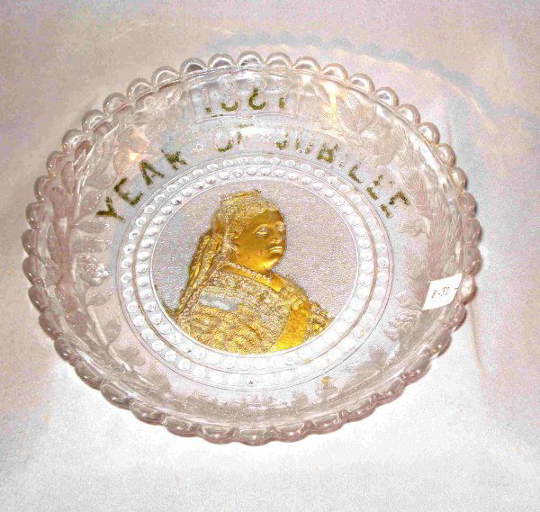 Glass and painted Victoria commemoration plate: A pressed glass 8 1/2" shallow dish commemorating the Jubilee years of reign for Queen Victoria, issued in 1887. Has remaining traces of gold.